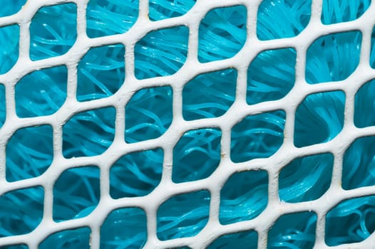 Metal enameled grid. abstract background. blue cloth behind the metallic grate. iron white mesh