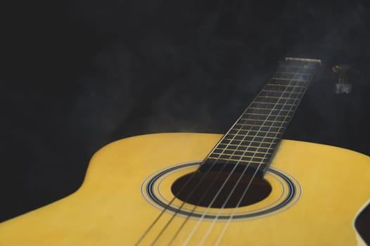 Acoustic guitar in smoke close up. musical instrument. strings on the guitar fretboard
