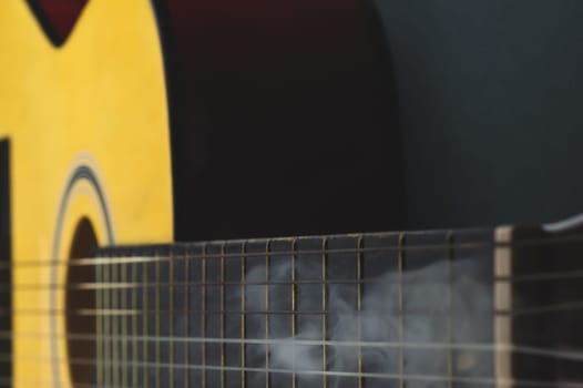 Acoustic guitar in smoke close up. musical instrument. strings on the guitar fretboard