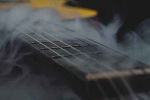Acoustic guitar in smoke close up. musical instrument. strings on the guitar fretboard