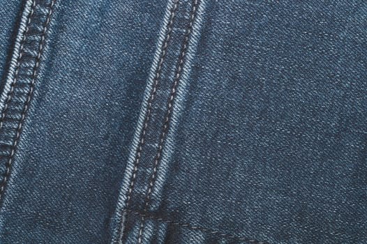 Jeans background with seams. denim texture close up. fabric backdrop with stitches