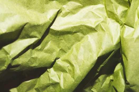 Crumpled green paper close up. creased kraft paper material
