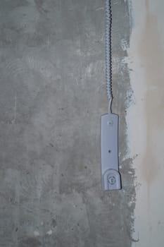 Intercom phone receiver on gray concrete background. handset hanging on the wire close up