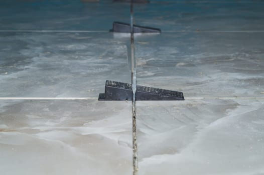 Tile leveling system. plastic clips for laying granite tiles on the floor close up