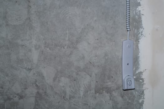 Intercom phone receiver on gray concrete background. handset hanging on the wire close up
