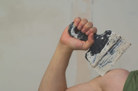 Hand holds construction spatula with putty. trowel with spackling. process of renovation