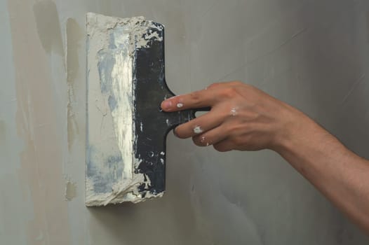 Hand holds construction spatula with putty. trowel with spackling. process of renovation