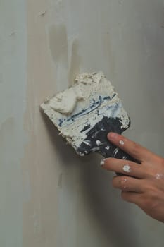 Hand holds construction spatula with putty. trowel with spackling. process of renovation