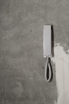 Intercom phone receiver on gray concrete background. handset on the wall close up
