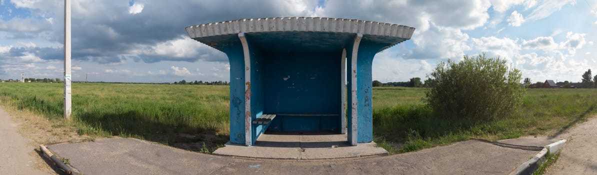 Rural bus stop on the country road with the field on the background