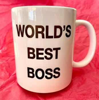 "World's Best Boss"" on a white mug with a pink background"