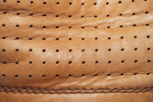 Brown leather texture with holes and stitches. creased material with seams macro background