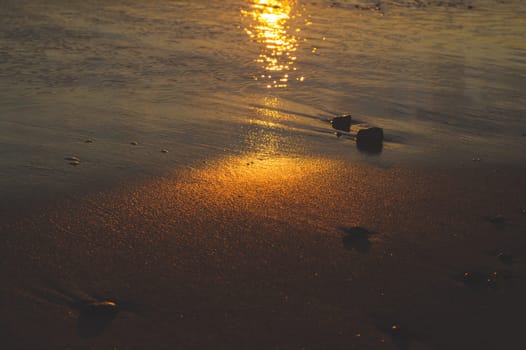 Wet sand on the beach at the evening. golden sunset over the sea