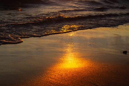 Wet sand on the beach at the evening. golden sunset over the sea