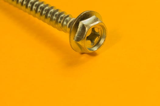 Steel screw on a yellow background. working tools