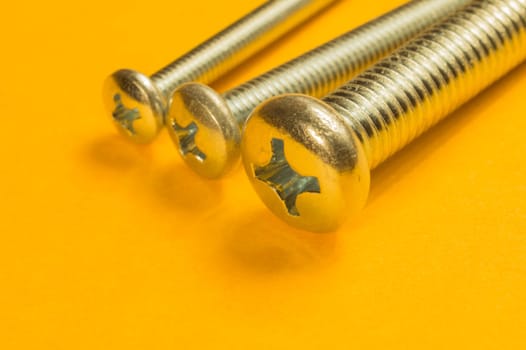 Steel screw on a yellow background. working tools