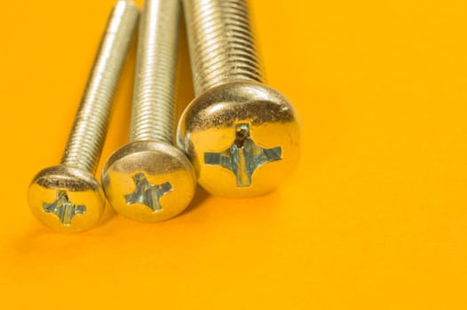 Steel screw on a yellow background. working tools