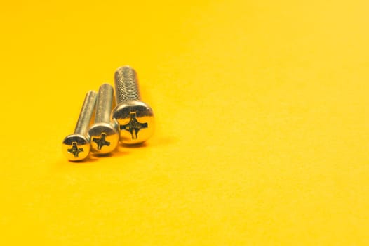 Steel screw on a yellow background. working tools