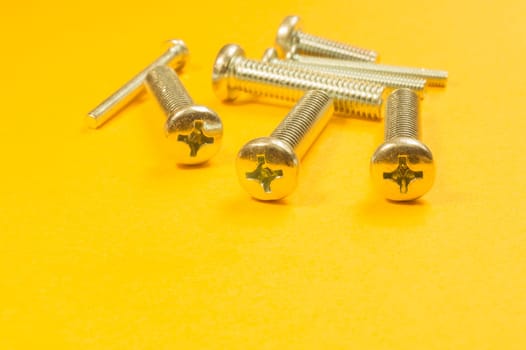 Steel screw on a yellow background. working tools