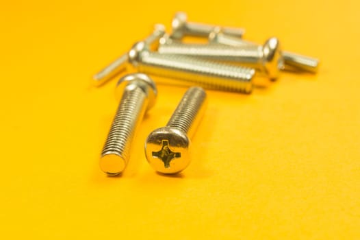 Steel screw on a yellow background. working tools