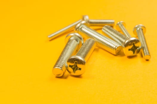 Steel screw on a yellow background. working tools