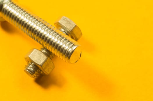 Steel screw on a yellow background. working tools