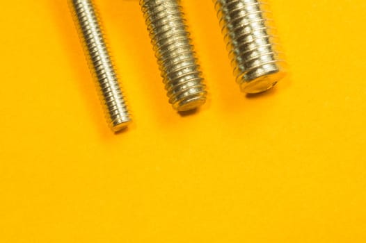 Steel screw on a yellow background. working tools