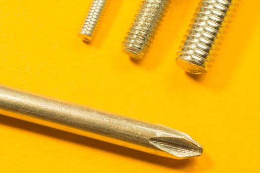 Steel screw on a yellow background. working tools