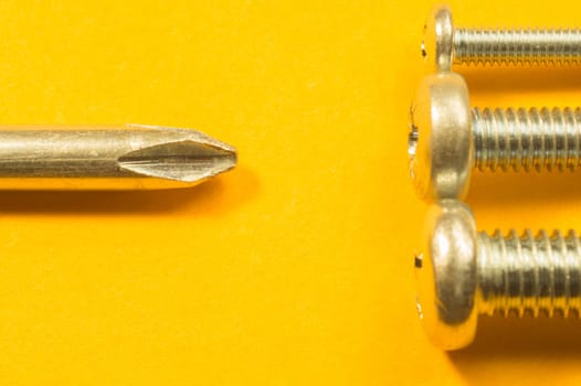Steel screw on a yellow background. working tools