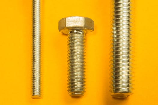 Steel screw on a yellow background. working tools