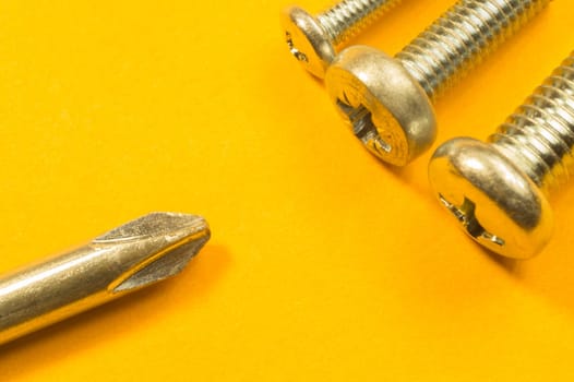 Steel screw on a yellow background. working tools