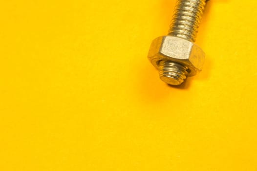 Steel screw on a yellow background. working tools
