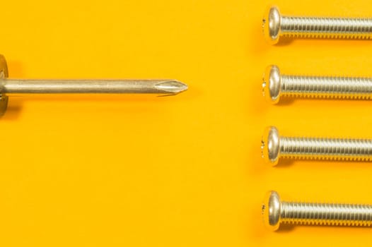 Steel screw on a yellow background. working tools