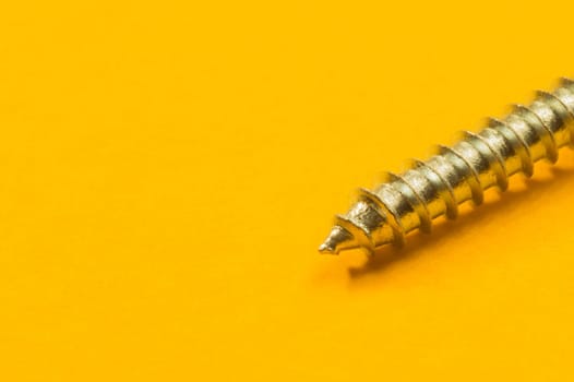 Steel screw on a yellow background. working tools
