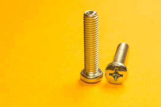 Steel screw on a yellow background. working tools