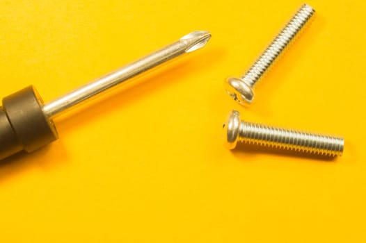 Steel screw on a yellow background. working tools
