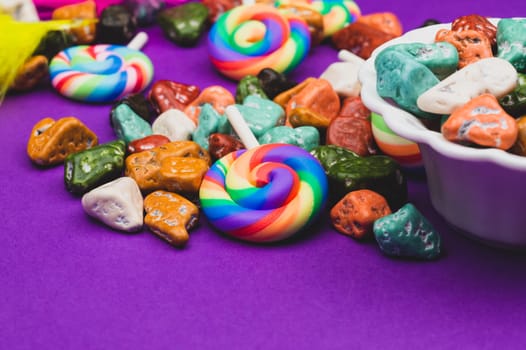 Lollipops and candy pebbles. sweets in the form of colored stones. colored background with colorful candies. copy space