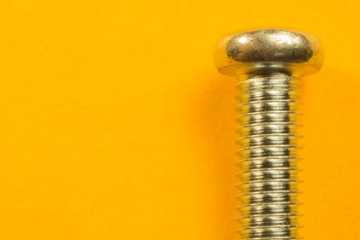 Steel screw on a yellow background. working tools