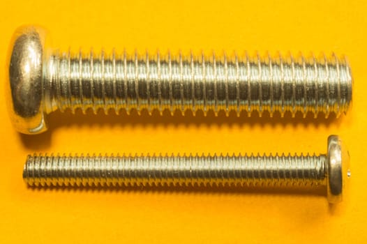 Steel screw on a yellow background. working tools