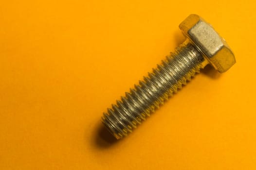 Steel screw on a yellow background. working tools