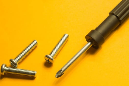 Steel screw on a yellow background. working tools