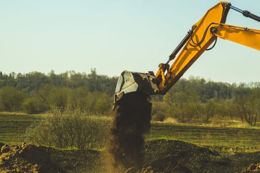 Excavator digs the ground. part of construction earthmoving equipment. digging and filling the soil with an excavator bucket