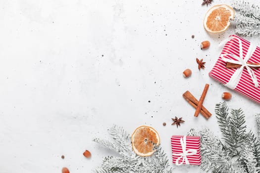 Christmas flat lay top view on white gray concrete background table with present red gift boxes, decorations, cinnamon sticks, hazelnut, dried orange slices, various spices, fir, anise, aniseed
