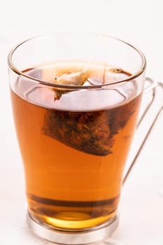 Steeping a herbal tea bag in a glass tea mug close up
