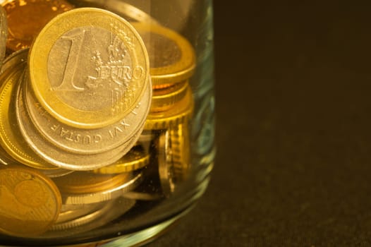 Coins of different countries in a glass jar. a lot of metal coins of different denominations and various countries. financial background. euro coin in the foreground