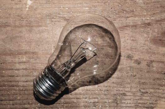 Light bulb on a wooden background. old lamp lies on the table.