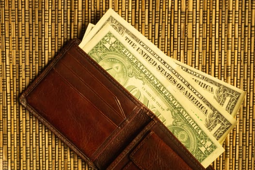 Dollars in a wallet on a wooden bamboo background. money on the table. finance background