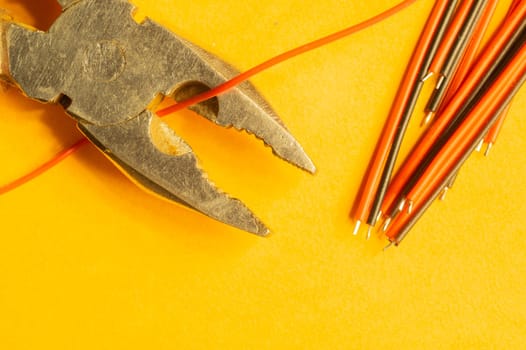 Pliers cuts a red wire on yellow background. work tool. copy space