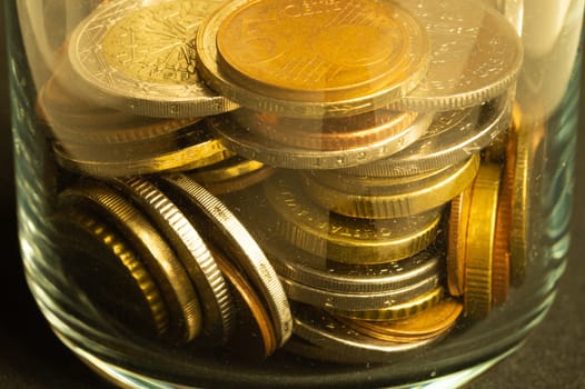 Coins of the different countries in a glass jar. a lot of metal coins of different denominations and various countries. finance background
