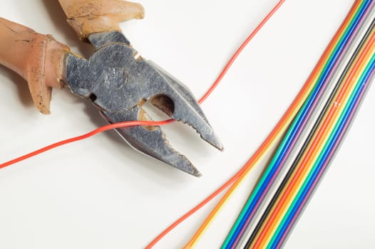Pliers cuts a red wire on white background. pliers with colorful wires. work tool